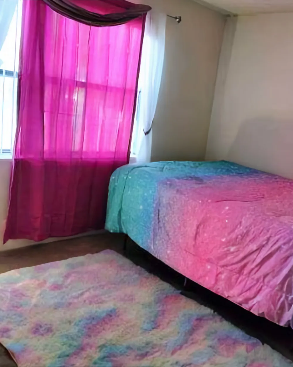 The same bedroom after cleaning, with the bed made and a rug on a clear floor