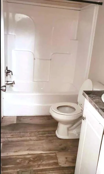The same bathroom with a clear floor and a white tub and toilet