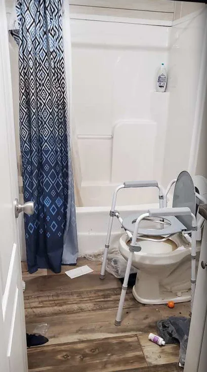 A bathroom with items on the floor and a grimy tub surround