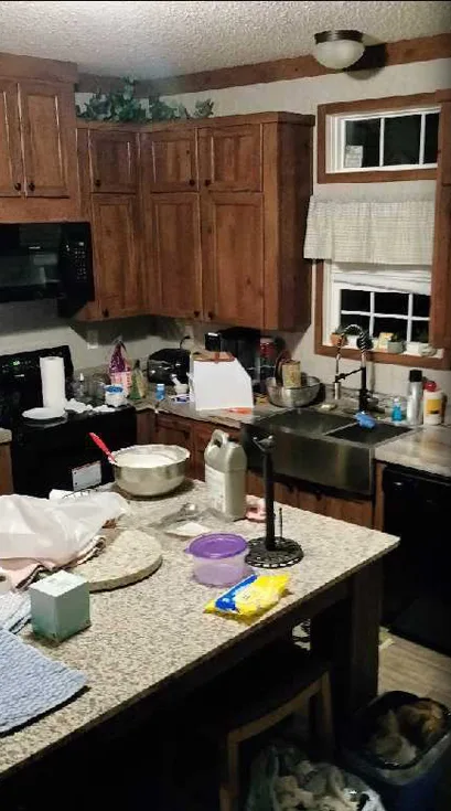 A kitchen with the counters and island covered in dishes, pots and food
