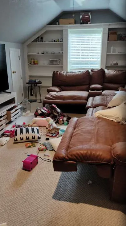 An upstairs living room with toys and clutter across the carpet