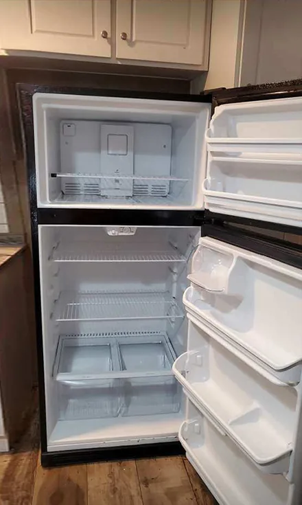 The same refrigerator emptied, with clean white shelves and drawers