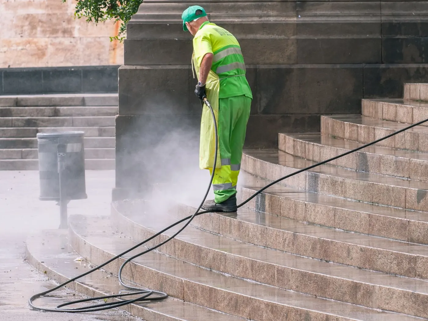 Stock photo of a worker pressure washing stone steps